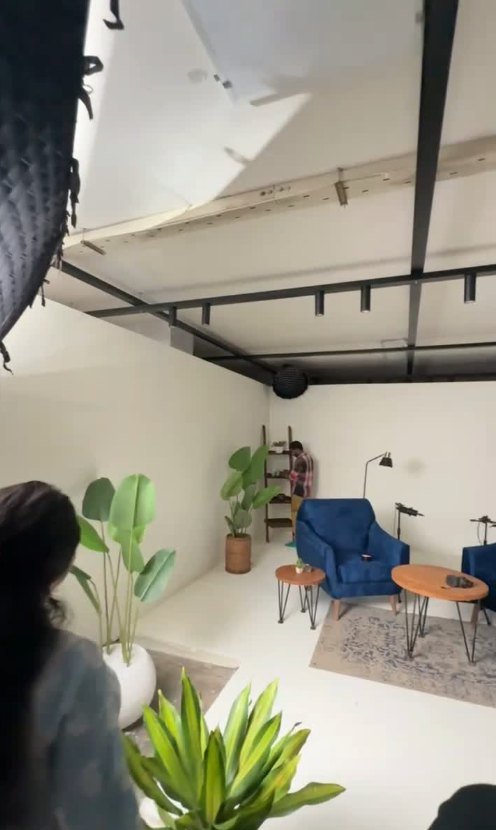 A podcast studio set designed by Mubah, with blue armchairs, plants and a round table